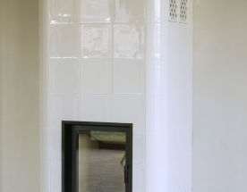 Nasze realizacje - Piece kaflowe NR-PK-48 - Piec kaflowy z białych błyszczących kafli. Do wkładu grzewczego podłączona masa kumulacyjna, która przez kilka godzin po wygaszeniu utrzymuje piec ciepły. projekt: Marcin Deręgowski