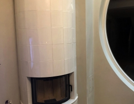 Nasze realizacje - Piece kaflowe NR-PK-51 - Piec kaflowy w narożniku z białych kafli z wkładem stalowo-szamotowym do którego podłączona jest ok. 150kg masa kumulacyjna. W górnej części zdobiony pasek z ręcznie malowanym relifem. projekt: Marcin Deręgowski