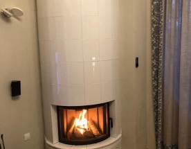 Nasze realizacje - Piece kaflowe NR-PK-55 - Okrągły piec kaflowy w narożniku, który w górnej części ma kafle ręcznie malowane. Do samego wkładu dołączona jest dodatkowa masa akumulacyjna - pozwalająca na utrzymanie ciepła kafli ponad 6h. projekt: Marcin Deręgowski